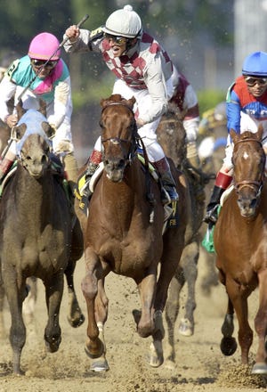Jockey Jose Santos raised his hand in victory after he rode Funny Cide to a win over Empire Maker, left, in the 129th Kentucky Derby at Churchill Downs. May 3, 2003